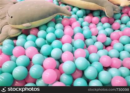 Children's dry pool with pink and blue plastic balls and soft toys whales.