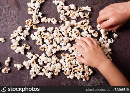 Children&rsquo;s hand holding a pile of fresh popcorn closeup. Children&rsquo;s hand holds popcorn