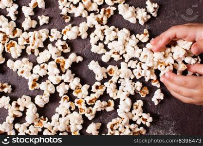 Children&rsquo;s hand holding a pile of fresh popcorn closeup. Children&rsquo;s hand holds popcorn