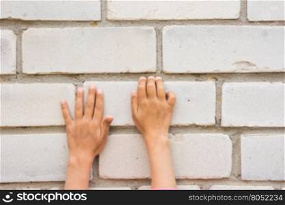 Children&rsquo;s hand trying to grab the tabs brick wall