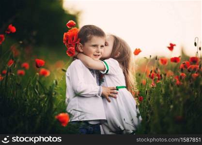 Children&rsquo;s love, a little boy and a girl, amicably spend time, laugh and smile, and kiss in the flowering field of poppies.. Children&rsquo;s love, a little boy and a girl, amicably spend time, laugh and smile, and kiss in the flowering field of poppies