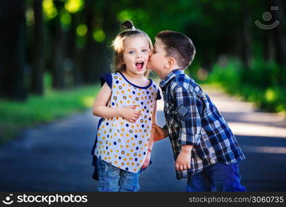 Children&rsquo;s love, a little boy and a girl, having fun, laugh and smile, and kiss outdoors.. Children&rsquo;s love, a little boy and a girl, having fun, laugh and smile, and kiss outdoors