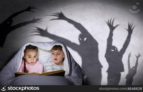 Children&rsquo;s nightmares. Children sitting in bed under blanket with book
