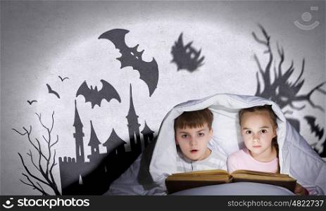 Children&rsquo;s nightmares. Children sitting in bed under blanket with book