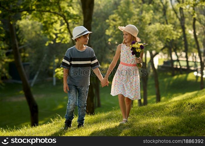 Children&rsquo;s romantic date in summer park, friendship, first love. Boy and girl with bouquet. Kids having fun outdoors, happy childhood. Children&rsquo;s date, boy and girl with bouquet