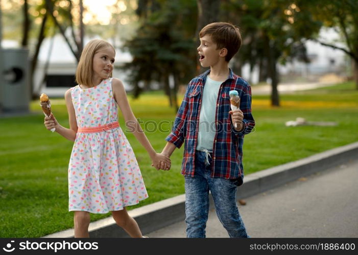 Children&rsquo;s romantic date in summer park, friendship, first love. Boy and girl eating ice cream. Kids having fun outdoors, happy childhood. Children&rsquo;s date, boy and girl eating ice cream