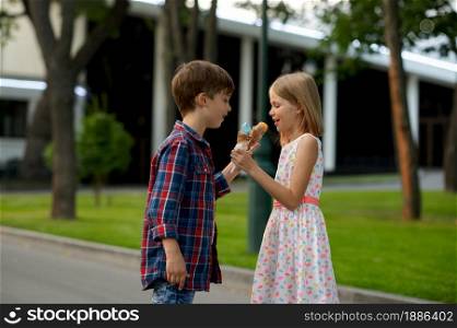 Children&rsquo;s romantic date in summer park, friendship, first love. Boy and girl exchange ice cream. Kids having fun outdoors, happy childhood. Boy and girl exchange ice cream, children&rsquo;s date