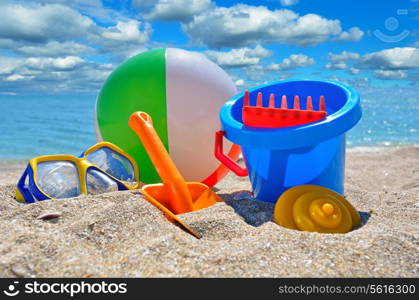 Children&rsquo;s toys on the beach against the blue sea and cloudy sky