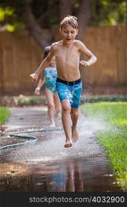 Children running in water on sidewalk