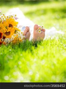 Children`s feet with spring flower on green grass
