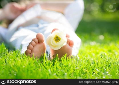 Children`s feet with spring flower on green grass