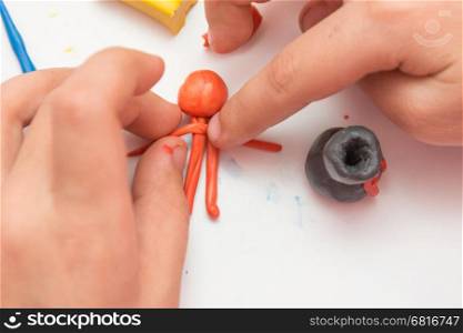 Children's hands molded man from clay