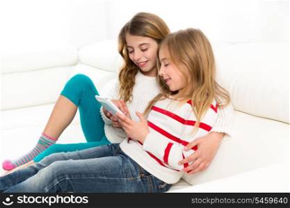 Children sister friends kid girls playing together with tablet pc on white sofa