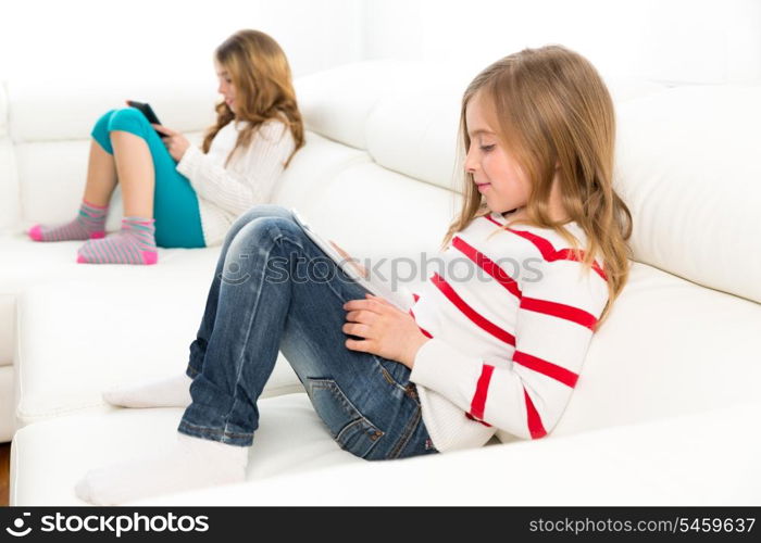 Children sister friends kid girls playing with tablet pc on white sofa