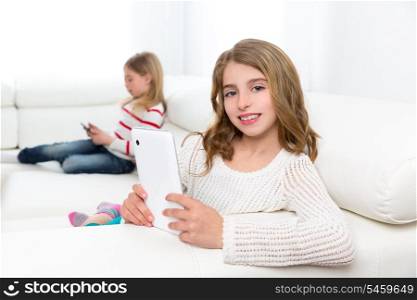 Children sister friends kid girls playing with tablet pc on white sofa