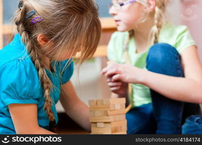 Children - sisters - playing at home with bricks