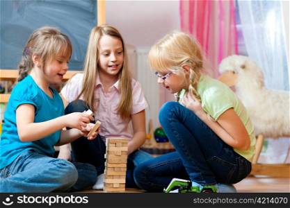 Children - sisters - playing at home with bricks