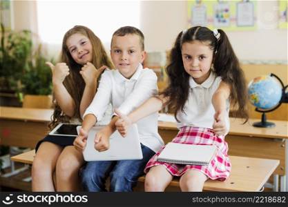 children sitting school desk gesturing