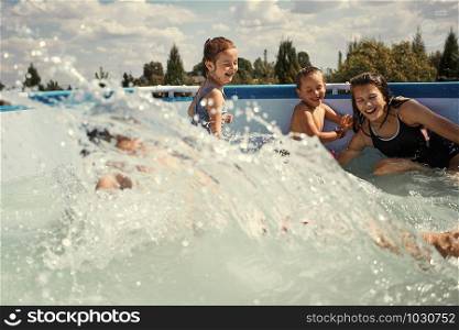 Children splashing, jumping, playing in a pool in backyard on summer vacation day. Real people, authentic situations