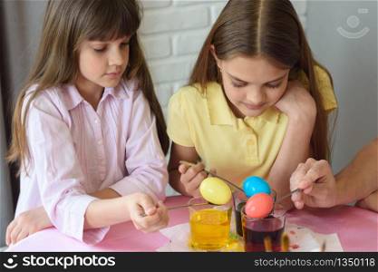 Children stain eggs in a special dye in glasses