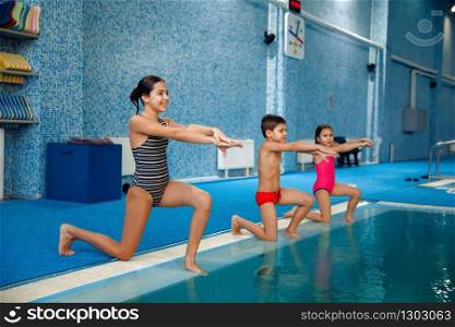 Children swimming group, workout at the poolside. Kids learns to swim in the water, sport training, fitness exercise in the pool. Children swimming group, workout at the poolside