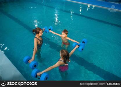 Children swimming group, workout with dumbbells in the pool. Kids learns to swim in the water, sport training, fitness exercise. Children swimming group, workout with dumbbells