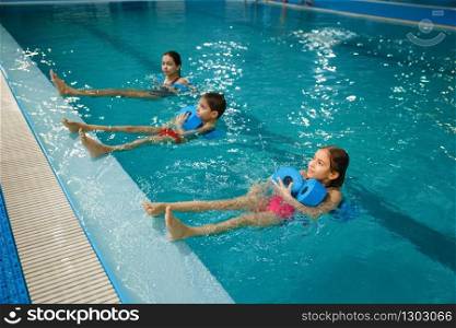 Children swimming group, workout with dumbbells in the pool. Kids learns to swim in the water, sport training, fitness exercise. Children swimming group, workout with dumbbells