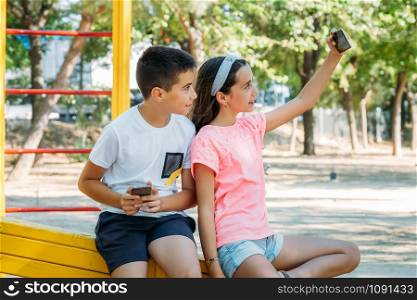 children taking a selfie with their cell phone in a park