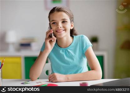 children, technology and communication concept - happy smiling girl distracting from homework and calling on smartphone at home