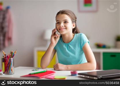 children, technology and communication concept - happy smiling girl distracting from homework and calling on smartphone at home. happy girl calling on smartphone at home