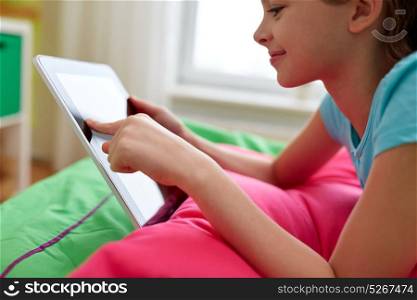 children, technology and communication concept - smiling girl with tablet pc lying on bed at home. smiling girl with tablet pc lying on bed at home