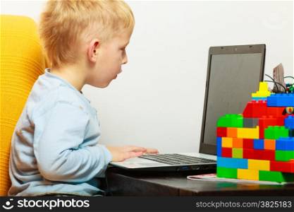 Children, technology and home concept - little boy kid child using laptop pc computer at home