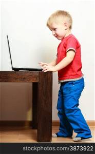 Children, technology and home concept - little boy kid child using laptop pc computer at home