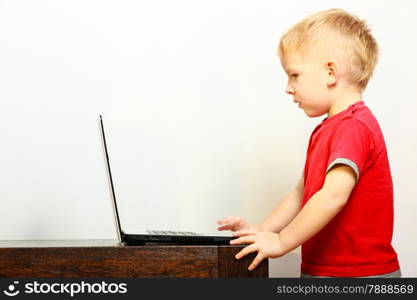 Children, technology and home concept - little boy kid child using laptop pc computer at home