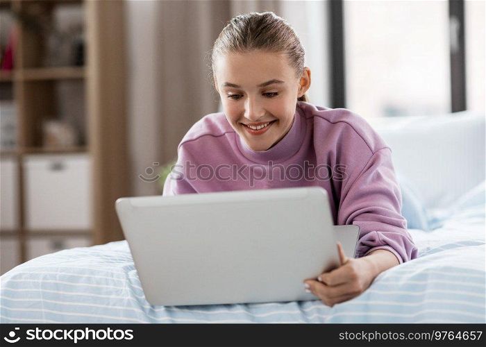 children, technology and internet concept - happy smiling student girl with laptop computer at home. smiling girl with laptop computer at home