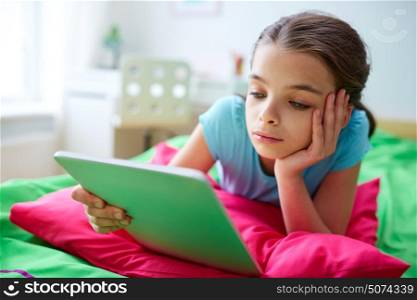 children, technology, people and communication concept - bored girl with tablet pc lying in bed at home. smiling girl with tablet pc lying in bed at home