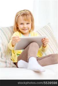 children, toys, technology and happiness concept - smiling little girl with tablet pc computer sitting on sofa at home