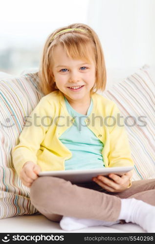 children, toys, technology and happiness concept - smiling little girl with tablet pc computer sitting on sofa at home