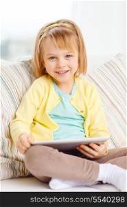 children, toys, technology and happiness concept - smiling little girl with tablet pc computer sitting on sofa at home