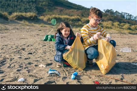 Children volunteers picking up trash on the beach. Children volunteers cleaning the beach