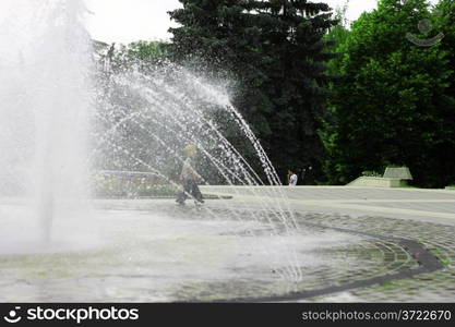 Children walking around splashing fontain in the center of the town