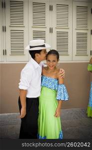 Children wearing Plena traditional attire kissing, outdoors