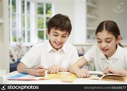 Children Wearing School Uniform Doing Homework In Kitchen