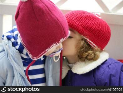 Children, winter red hat dressed whispering secrets in ear