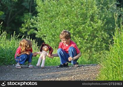 Children with doll on path in park