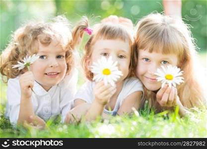 Children with flowers lying on green grass in spring park