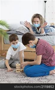 children with medical masks playing jenga home with mother