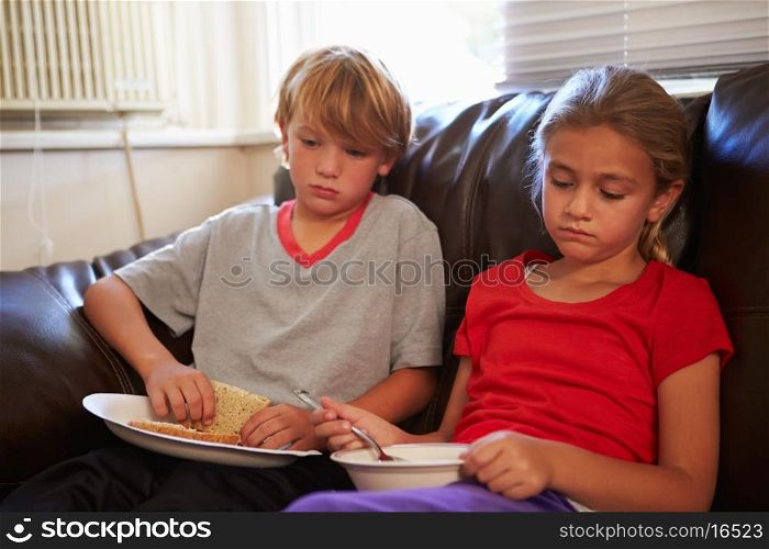 Children With Poor Diet Eating Meal On Sofa At Home