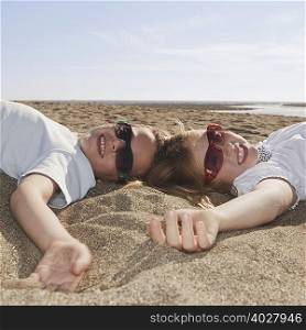 Children with sunglasses laying on sand