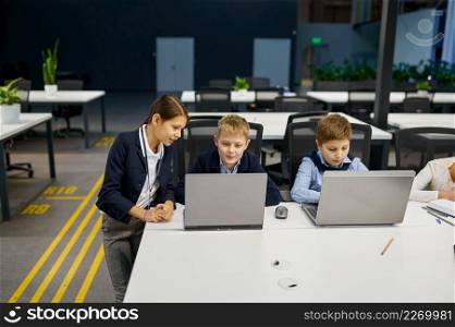 Children working using laptop in modern office. IT education with kids in computer school class. Children working on laptop in modern office